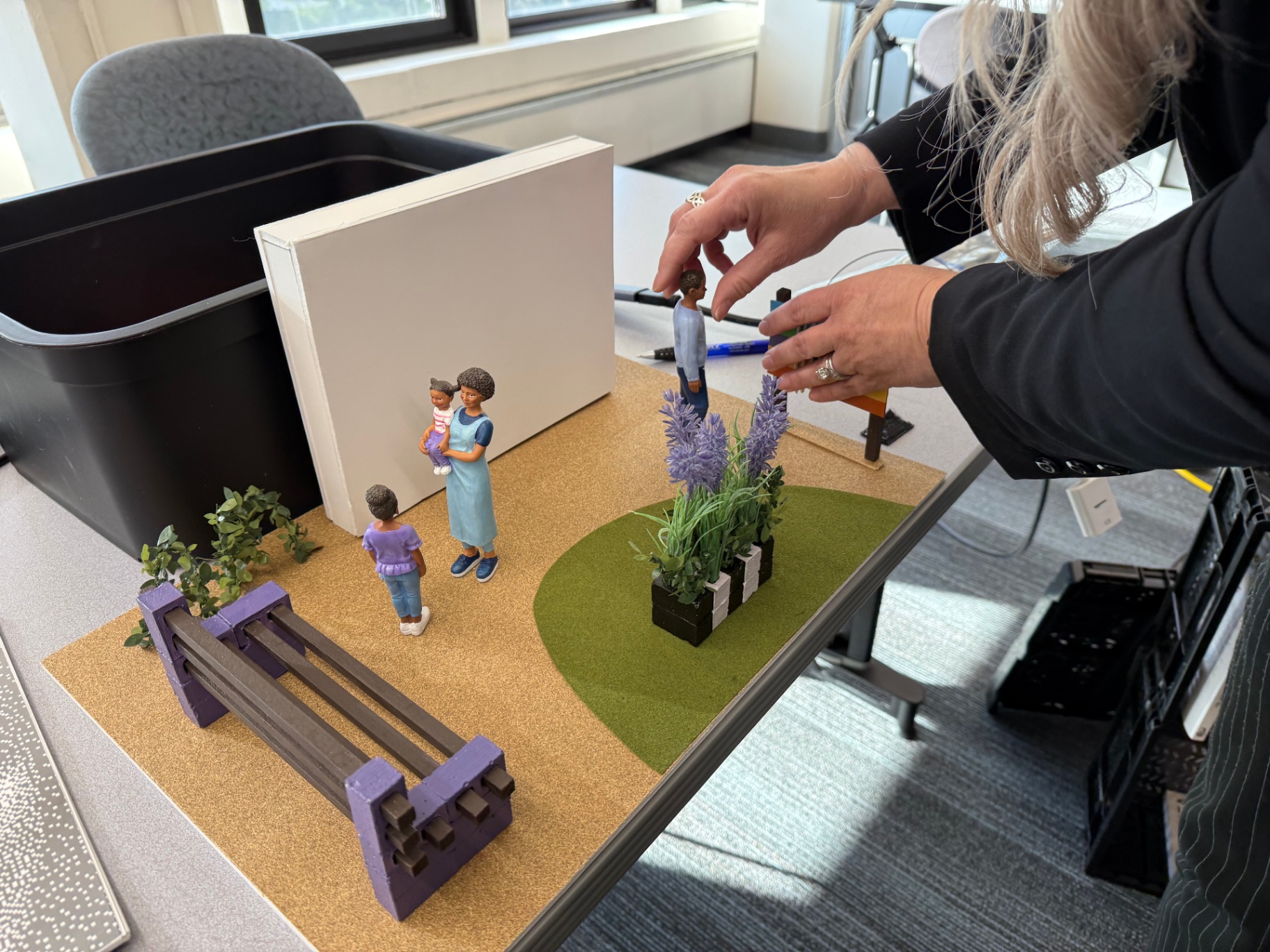 Scale model of a healing courtyard with figures, planters and seating