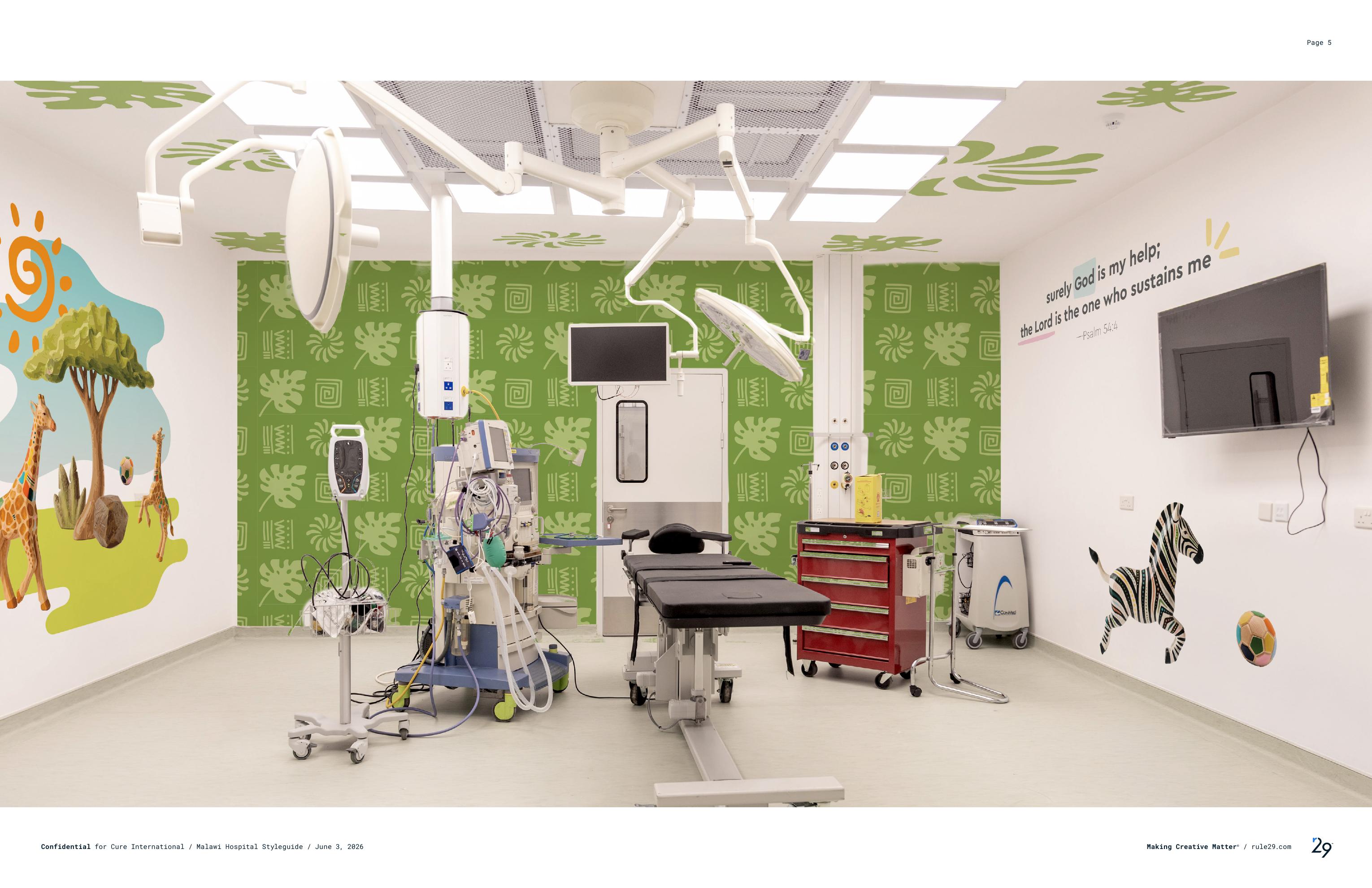 Installed operating room with green leaf and spiral pattern wall, giraffe and zebra murals, and Psalm 54:4 scripture wall